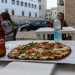 E le tovaglie sono bandite: le pizze si mangiano direttamente nel cartone accompagnate da una Peroni sudata